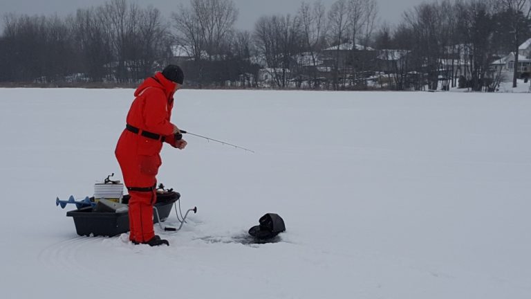 Ice angler drilling hole on frozen Lake St. Clair